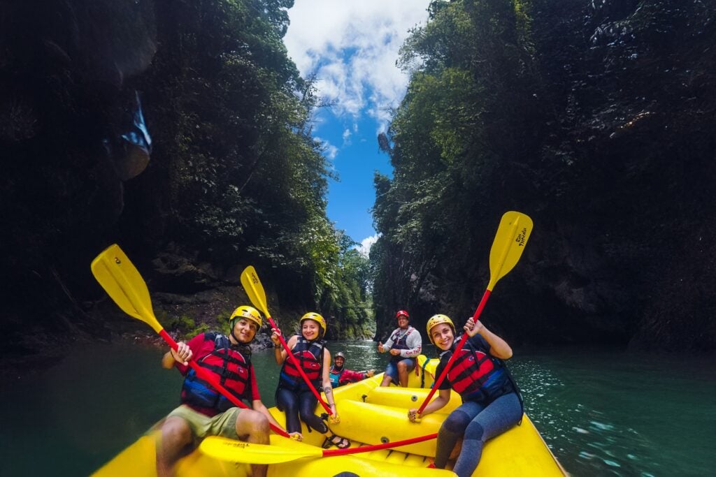 Grupo de turistas praticando rafting em botes amarelos no Río Pacuare, Costa Rica, cercados por cânions e floresta tropical.